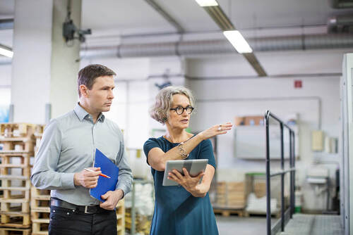 Managerin diskutiert mit männlichen Arbeitnehmer in der Druckerei.