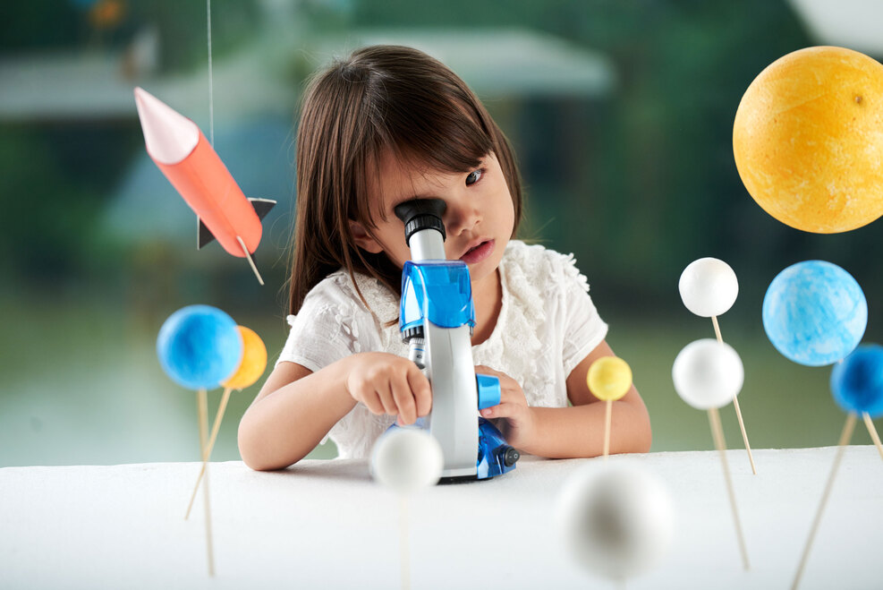 Ein kleines Mädchen schaut in ein Mikroskop